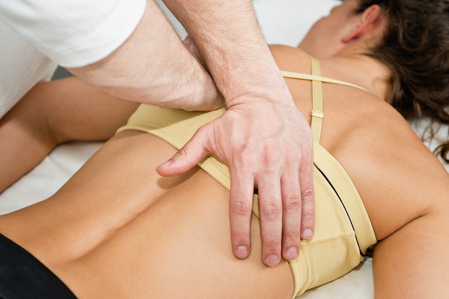blog picture of lady lying down with hands of chiropractor doing adjusting on back