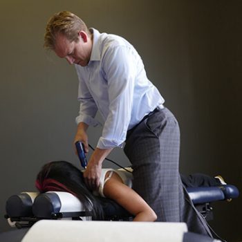 blog picture of chiropractor using machine to do an adjustment on lady's back