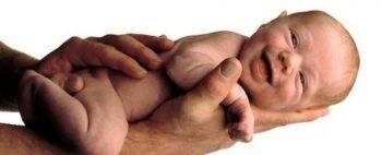blog picture of naked baby being held by chiropractor