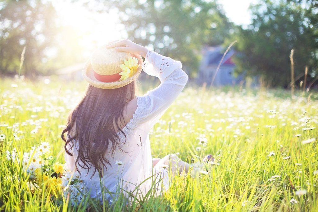 blog picture of a woman sitting in a field of flowers with the sun shining