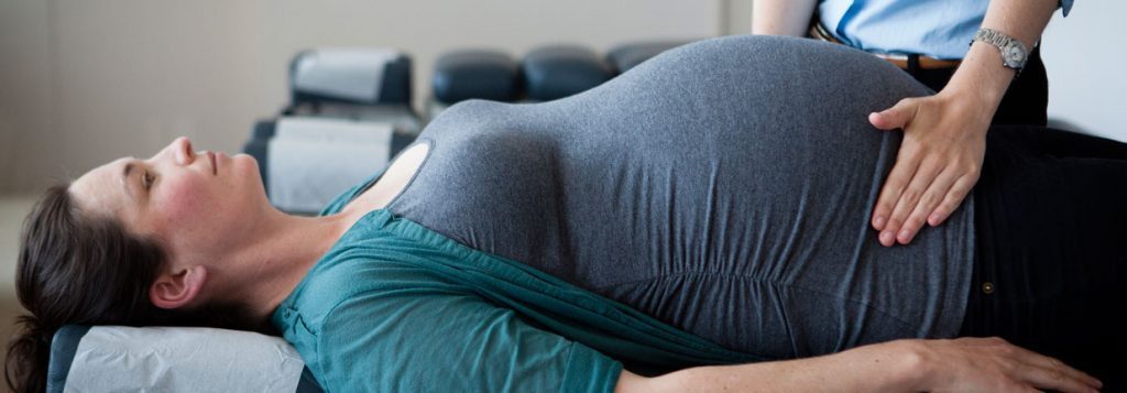bog picture of pregnant woman being checked by chiropractor