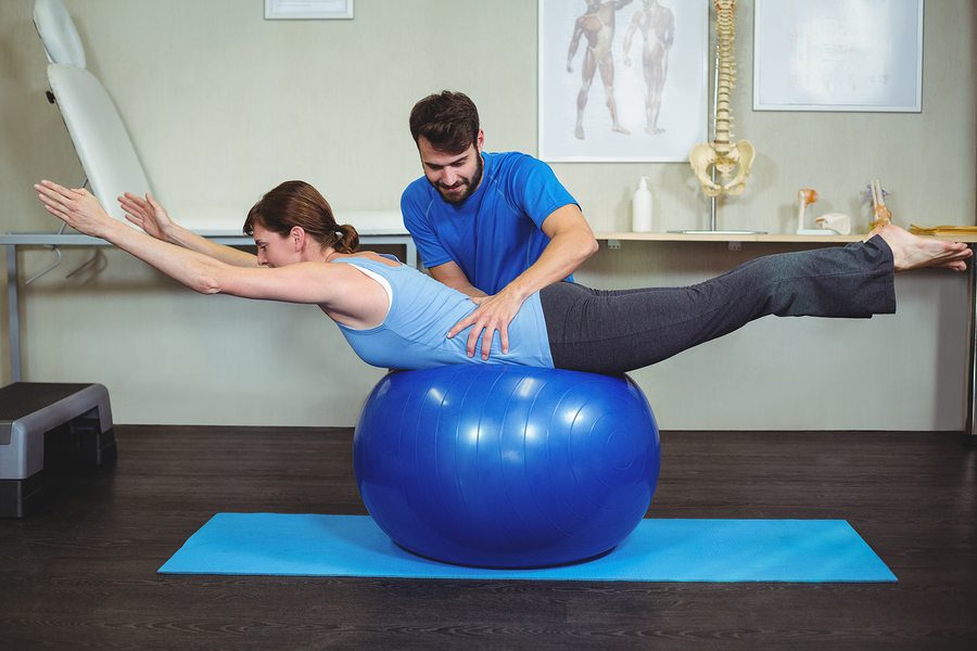 blog picture of Physiotherapist assisting woman on exercise ball in the clinic