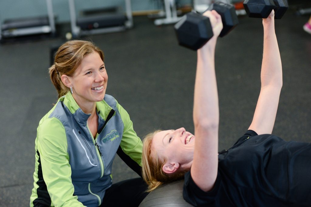 blog picture of woman working out with female trainer spotting