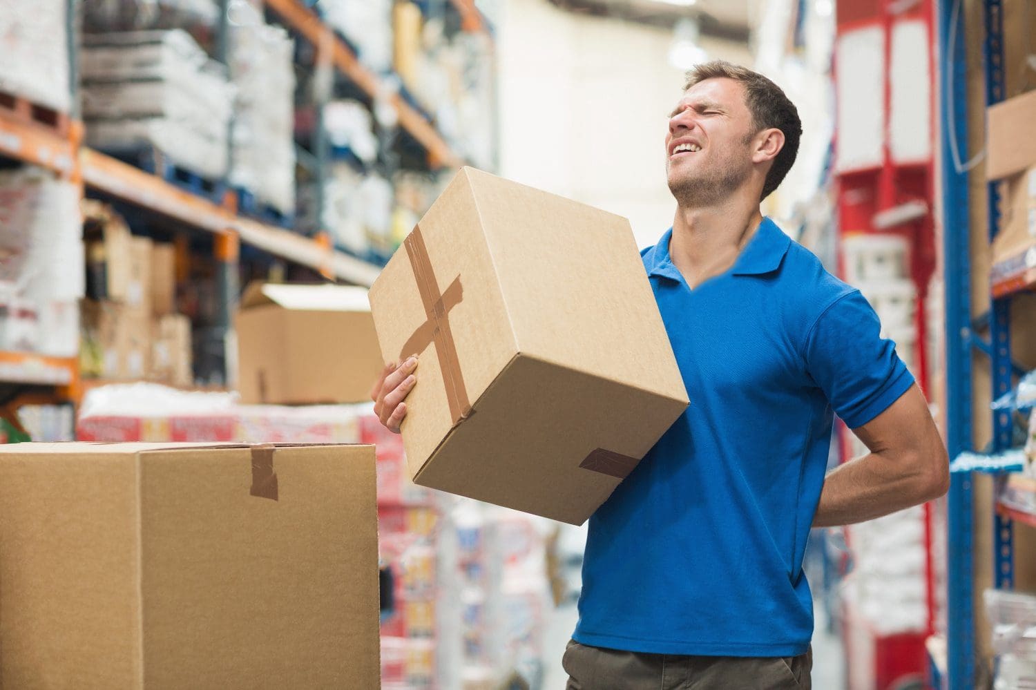 worker with backache while lifting box in the warehouse