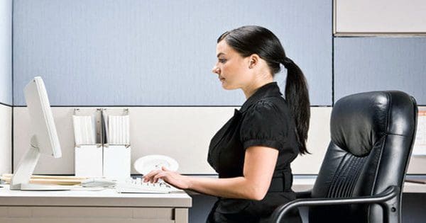 Señora sentada cunha boa postura na mesa de oficina