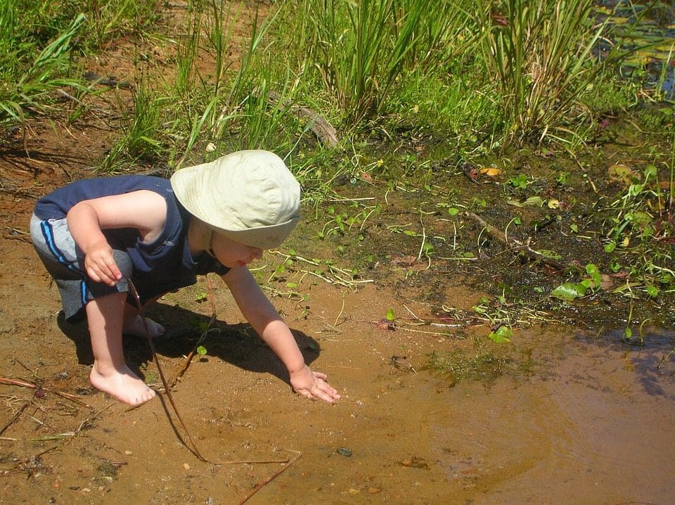 baby loopt in het gras en de modder